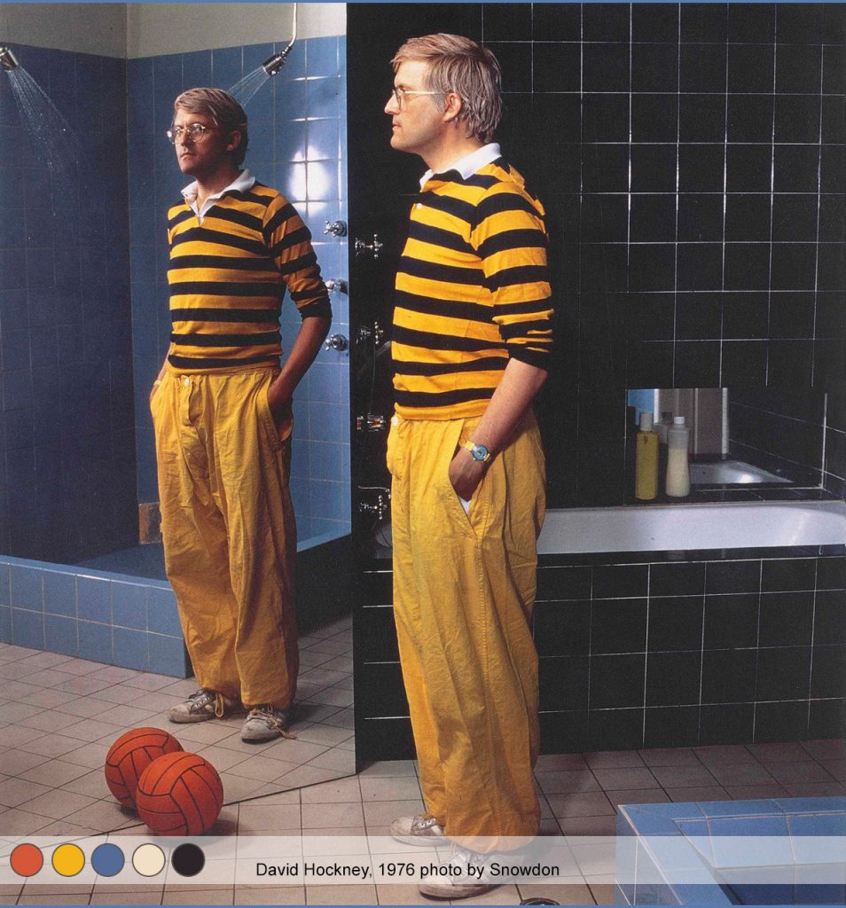 David Hockney wearing yellow trousers and a yellow and black stripped rugby shirt